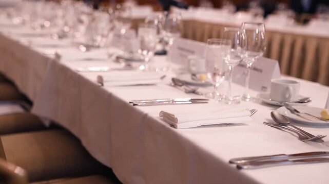 Cinematic footage of an elegant banquet table setting with crystal glassware, silverware, and a microphone, perfect for formal events and weddings.
