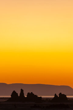 Limestone chimneys stand silhouetted against a vivid orange sunset sky, Afar depression, Lake Abbe, Djibouti