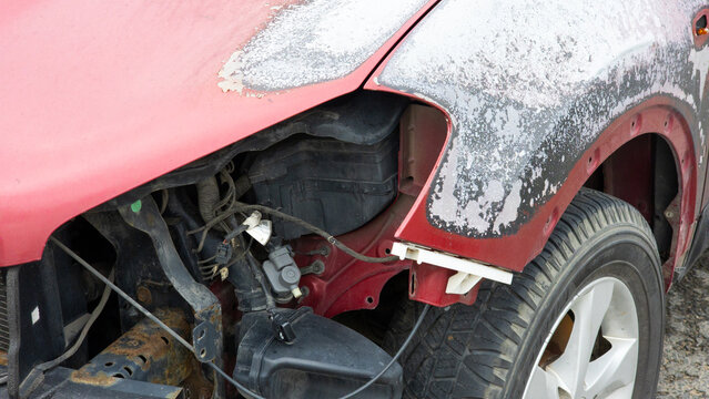 Fire damaged car after a road accident with exposed internal components and destroyed body panels, representing vehicle damage, insurance claims, road safety and post collision consequences