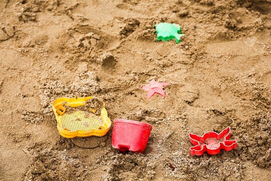 Children's colorful plastic beach toys lying on sand