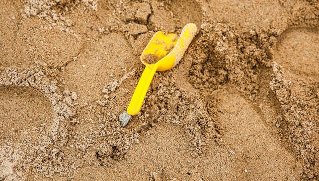 Yellow toy shovel lying in brown sand