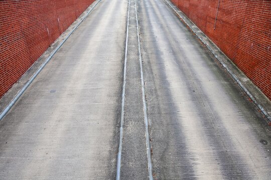 Concrete pathway with brick walls and parallel lines