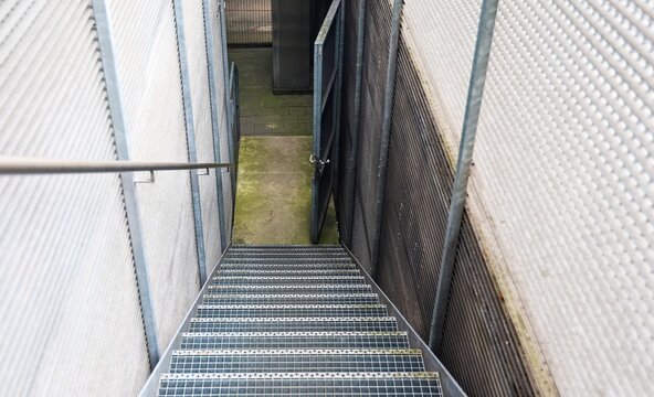 Metal staircase descending into an enclosed industrial basement