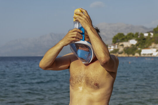 Man adjusting snorkeling mask on a sunny Croatian beach shorelin