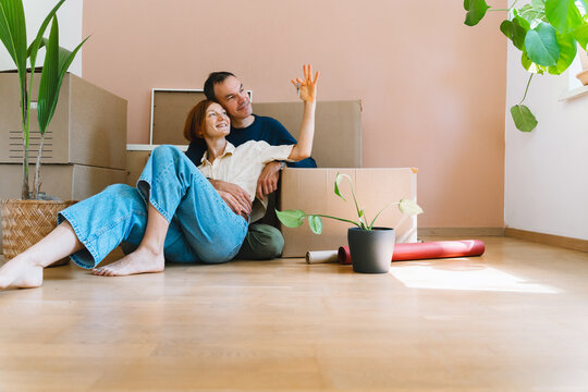 A mature caucasian woman proudly holds up keys to their new apartment while sitting beside her husband. Real estate investment and successful property purchase concept.