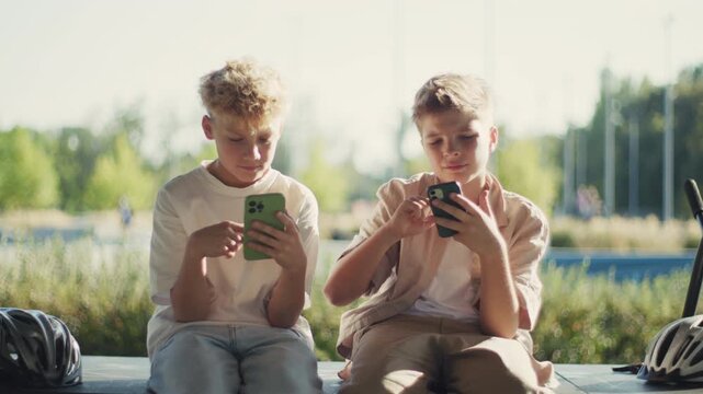Two 10 Year Old Boys Phubbing and Using Smartphones in Park