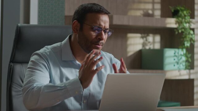 Annoyed angry Indian American business man frustrated working laptop indoor office rubbing hands worried businessman male loss bet mistake trading broker failure wrong password data bad result problem