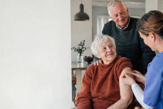 Senior woman receiving vaccine injection beside husband