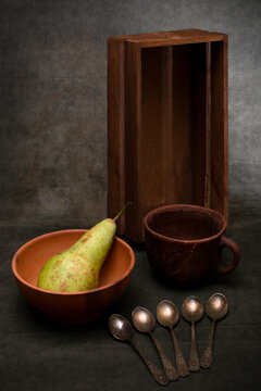 Still life with a box, a ripe pear, a cup, and teaspoons