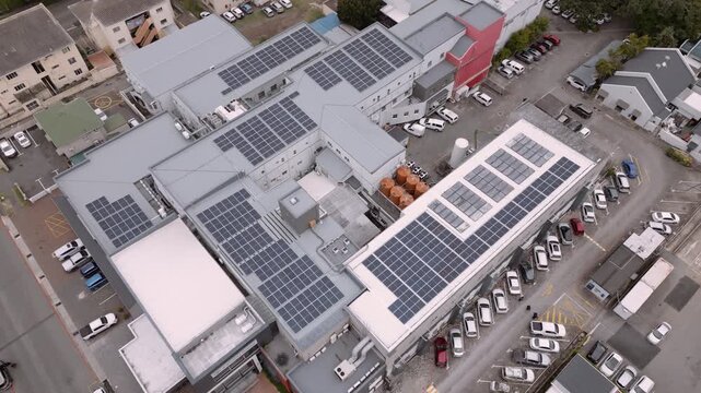 Compact hospital complex with rooftop solar arrays and water storage tanks viewed from above, showing off-grid infrastructure.
