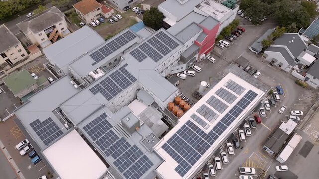 Compact South African hospital complex with rooftop solar arrays, orange water tanks, and busy parking lots seen from above.