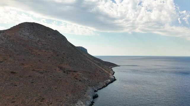 Seitan Limania coastline follows the rugged limestone cliffs of the Akrotiri Peninsula near Chania, Crete, Greece, with a barren rocky slope meeting the Cretan Sea, aerial shot