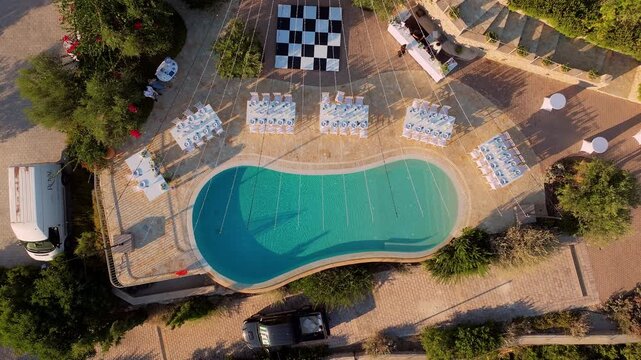 Aerial view of a wedding reception setup at Ormos Luxury Villas in Kranidi, Greece, with a checkered dance floor, pool, and elegant tables arranged along the terrace.