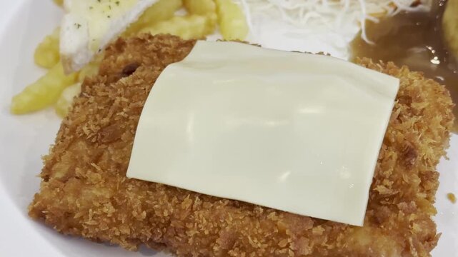 Crispy breaded chicken cutlet with melted cheese, french fry, gravy, rice, toast, and salad
