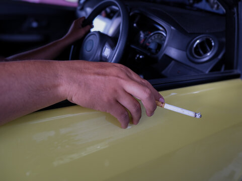 Man Holding Cigarette Out of Car Window While Driving Vehicle