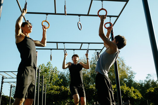 Energetic Gen Z Male Athletes Practicing Calisthenics Training at Outdoor Sports Park.