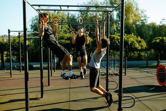 Active Gen Z Teen Boys Enjoying Group Calisthenics Workout at Outdoor Sports Park.