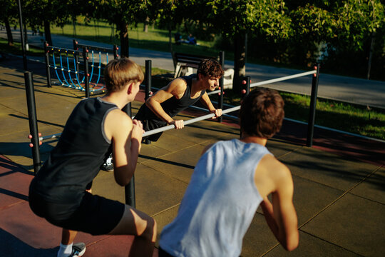 Active Gen Z Teen Boys Enjoying Group Calisthenics Workout at Outdoor Sports Park.
