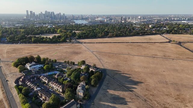 Climate change drought near Canary Wharf London aerial view of Blackheath and Greenwich Park with brown dry grass and city skyline