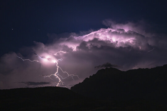 Lightning strike illuminating storm clouds over mountain
