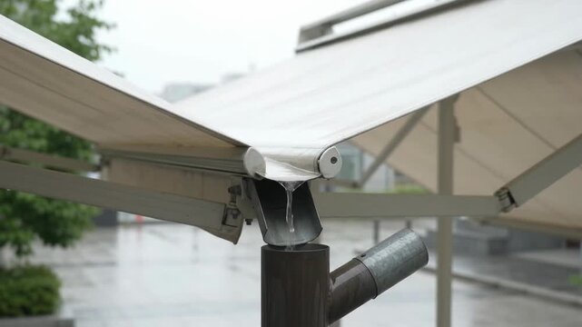 Rainwater Pours From Awning Into Metal Downspout