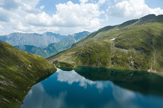 Wilderness travel and ecotourism, scenic aerial view of an alpine lake in the Kitzb&uuml;hel Alps within Hohe Tauern National Park in Austria with mountain peaks and summer clouds