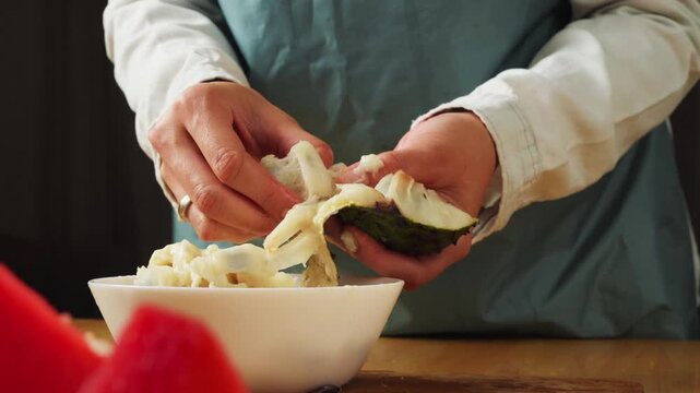 Fresh soursop pulp being separated from the peel by hand