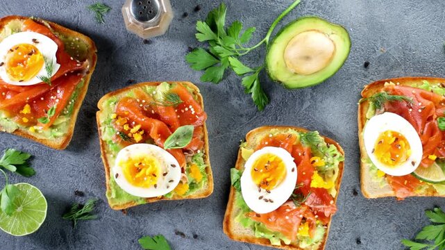 Healthy avocado toast with smoked salmon and egg on dark background overhead view