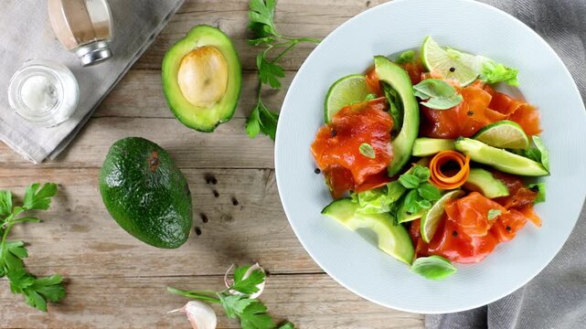 Healthy smoked salmon and avocado fresh salad on rustic wooden table overhead view