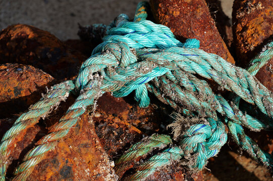Close-up of weathered turquoise ropes and heavily rusted chains in the fishing village of Ure, Lofoten, marked by years of use in a maritime environment.