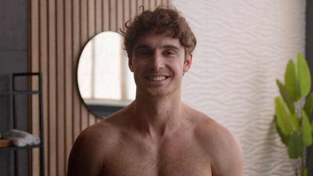Close up portrait of happy smiling Caucasian man in bathroom showing healthy teeth joyful shirtless male with clear skin carefree glad guy indoors enjoying morning beauty routine hygiene healthcare