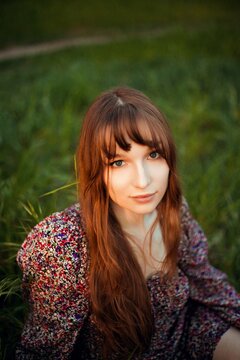 Young woman sitting in grass during sunset in a park