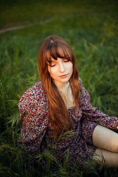 Young woman sitting in grass during sunset in a park