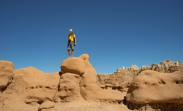 Tourist, young man likes Hodoo, eroded Hoodoos, rock formation of Entrada sandstone, Goblin Valley State Park, San Rafael Reef, Utah, southwest, USA