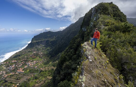 Hikers on the ridge of Pico do Alto, view of the coast and sea with the village of Arco de Sao Jorge, Madeira, Portugal