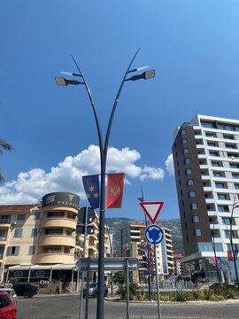 Low-angle view of a street lamp pole displaying the flags of Montenegro and Budva in Budva, Montenegro on August 9, 2026