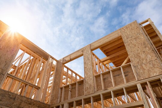 The Wooden House Frame Under Construction in Bright Sunlight with Blue Sky