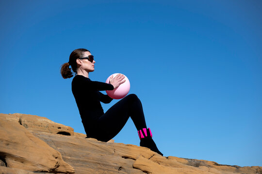 Woman in Black Sportswear on Sandstone Rocks with Pink Pilates B