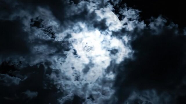 Full moon shines bright in the night sky with clouds surrounding it