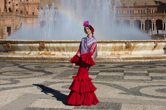 A beautiful woman dancing flamenco in a square in Seville, Spain. She is wearing a red ruffled dress and dances flamenco with great skill. Flamenco, a UNESCO Intangible Cultural Heritage.