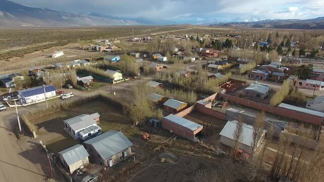 4K drone aerial view over Lago Posadas village in Santa Cruz, Argentina, revealing homes surrounded by rugged Patagonian landscapes, arid terrain and remote wilderness scenery.