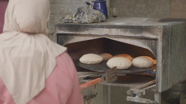Arab woman baking pita bread in the oven