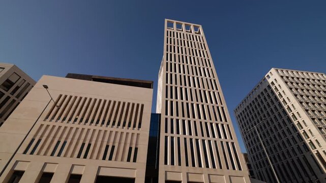 Wide view of an identifiable business complex with corporate names, flag banners, patterned paving and shallow reflecting pools.
