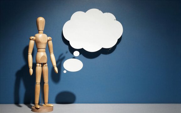 Wooden figure stands alone, shadowed by a blank thought cloud against blue wall.