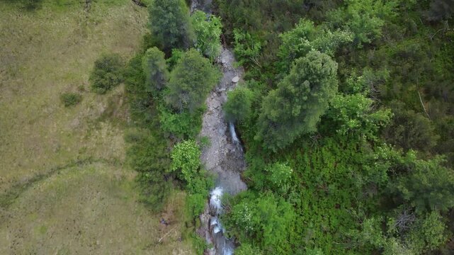 Alpine stream and waterfall in Hohe Tauern National Park, Austria, seen in an aerial drone tracking shot, showing this pristine mountain landscape