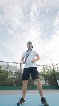Man prepares to serve on tennis court under cloudy sky during afternoon practice