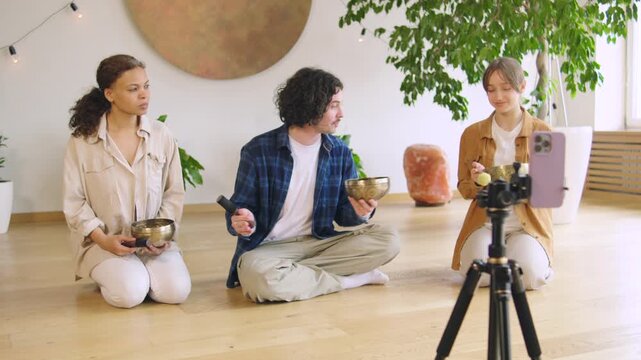 Group practices sound therapy in a studio setting with equipment and a camera recording the session for online sharing