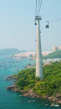 Longest Hon Thom cable car crossing over turquoise sea and lush green hills in Phu Quoc island, Vietnam. Cable car support tower with cable car cabin above tropical ocean. Modern tourism technology