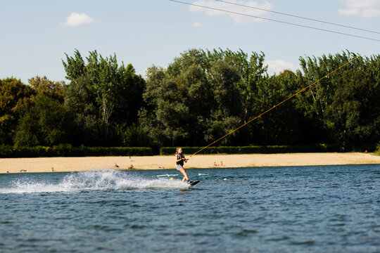 Female wakeboarder wakesurfing. Girl riding waterski cabel. Holding tow rope. Summer activities in the lake.