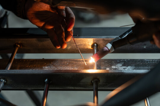 Gloved hands brazing a steel frame with an oxyacetylene torch